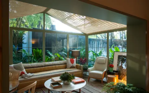 Acogedor solarium terraza con sofá a rayas, sillón, mesa de centro y exuberante vegetación.