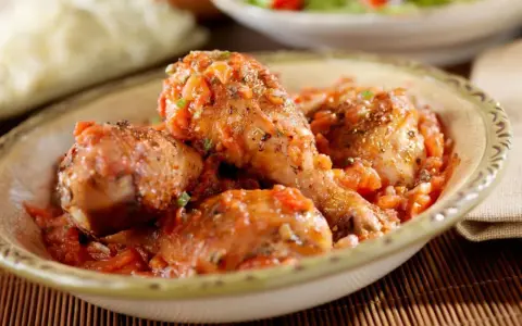Pollo en salsa de tomate con hierbas, servido en un cuenco rústico.