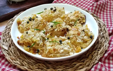 Deliziose cipolle al forno, dorate e croccanti, guarnite con rosmarino e pepe nero. Un contorno saporito e invitante.