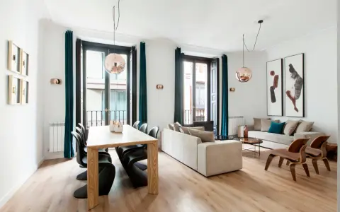 Amplio salón comedor rectangular de 25 metros con sofás, mesa de madera y sillas modernas.