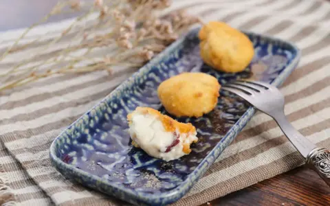 Deliciosa croqueta de jamón, cremosa por dentro y dorada por fuera, servida en un plato azul.
