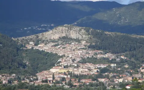 Borgo abruzzese arroccato su un colle, tra boschi e montagne. Immagina il **cammino dei briganti Abruzzo** che attraversa questi sentieri selvaggi.
