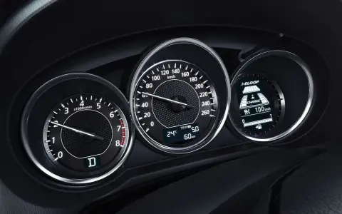 Deska rozdzielcza z obrotomierzem, prędkościomierzem i wyświetlaczem i-ELOOP. Widać falujące obroty silnika i prędkość 100 km/h.