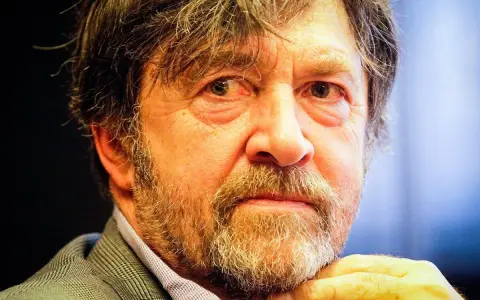 Zbliżenie na twarz Olek Krupa, z siwiejącą brodą i zmarszczkami wokół oczu.