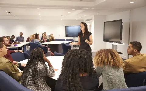 Docente spiega in aula, mentre gli studenti ascoltano. Forse sta parlando di quanto guadagna un professore universitario.