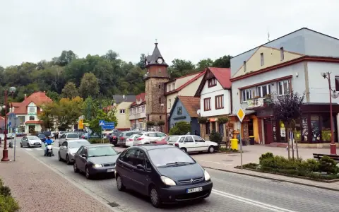 Tłoczny dobczyce rynek z wieżą zegarową, samochodami i skuterem.