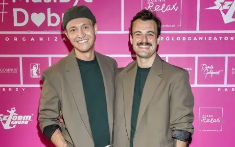 Kamil Krupicz i jego kolega pozują do zdjęcia na tle różowej ścianki z logotypami.