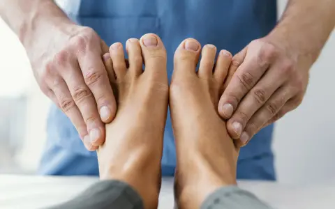 Fizjoterapeuta bada stopy pacjenta, aby zdiagnozować drętwienie palców u nóg.