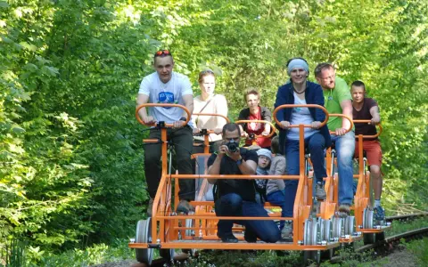 Rodzina na drezynach w Bieszczadach, ciesząca się zielenią i słońcem. Radość i wspólna przygoda na torach.