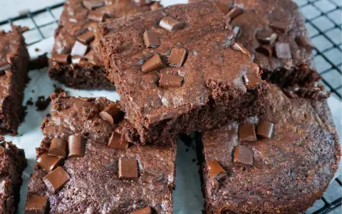 Saftige Zucchini Brownies mit Schokostückchen, die auf einem Gitterrost liegen.