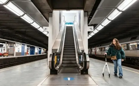 Kobieta z chodzikiem na dworcu kolejowym, gotowa na podróż pociągiem za granicę.