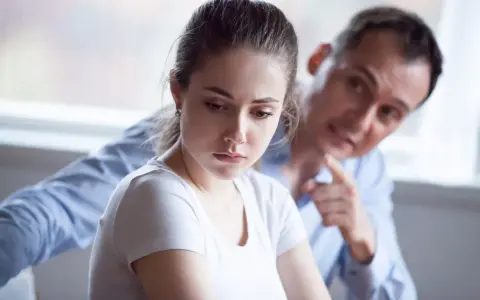 Mujer triste, hombre la señala. Una escena que evoca el trauma bonding español, donde el dolor crea un vínculo perverso.