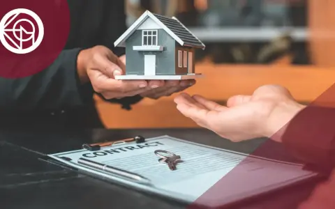 Manos entregan una maqueta de casa sobre un contrato y llaves. El IVA del alquiler de un local se desgrava.