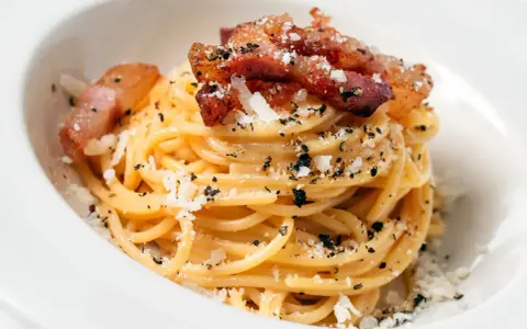 Pyszna carbonara z chrupiącym boczkiem, posypana parmezanem i pieprzem. Idealny boczek do carbonary to klucz do sukcesu.