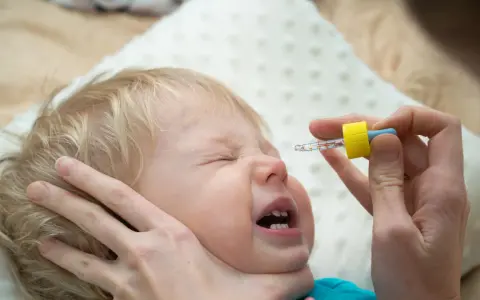 Ein Baby weint, während ihm N सेंटropfen verabreicht werden.