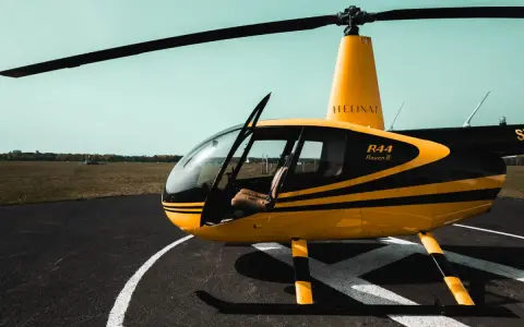 Żółto-czarny helikopter Robinson R44 Raven II na płycie lotniska. Marzysz, jak zostać pilotem helikoptera?