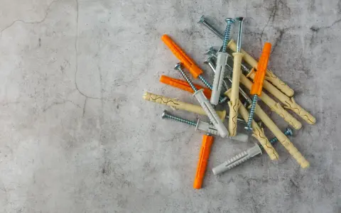 Montón de tacos de pared de varios colores (naranja, beige, gris) con tornillos. Listos para fijar cualquier cosa a la pared.