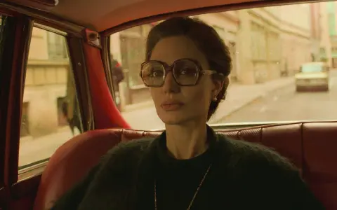 Angelina Jolie i en bil, en scen från en av hennes filmer. Hon bär stora glasögon och tittar ut genom fönstret.
