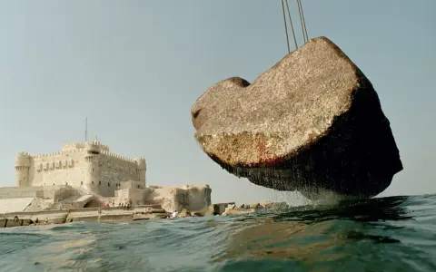Un bloc de pierre, vestige du phare d'Alexandrie, est soulevé au-dessus des eaux, près de la citadelle de Qaitbay.