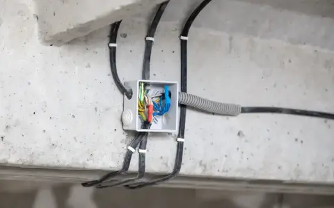 Rozdzielnica modułowa z przewodami elektrycznymi, zamontowana na betonowej konstrukcji.