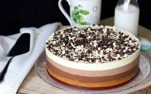 Deliciosa tarta de tres chocolates, con capas de blanco, con leche y negro, cubierta de virutas y bolitas de chocolate.