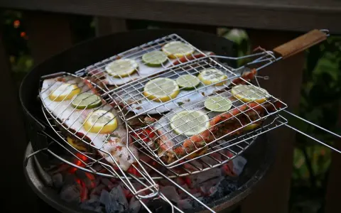 Grillad fisk med citron- och limeklyftor på en kolgrill. Doften av sommar och god mat sprider sig.