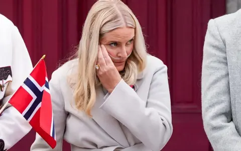 Kronprinsessan Mette-Marit med syrgasgrimma, en påminnelse om hennes sjukdom, håller en norsk flagga.