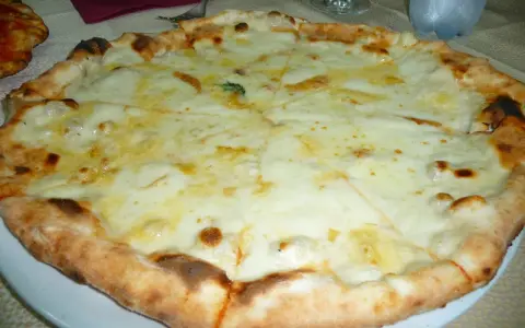 Pizza 4 formaggi appena sfornata, con crosta dorata e abbondante formaggio fuso.