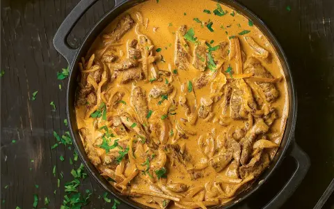 En gryta med krämig biff stroganoff, perfekt för ett mysigt middagsrecept. Garnerad med färsk persilja.