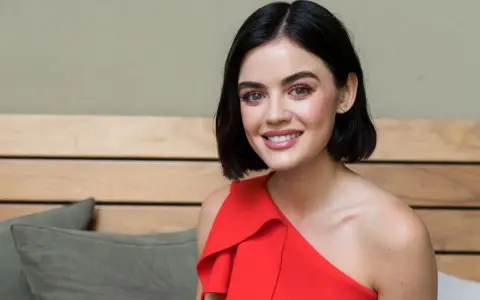 Lucy Hale sorride con un vestito rosso, ricordando i suoi film e programmi TV.