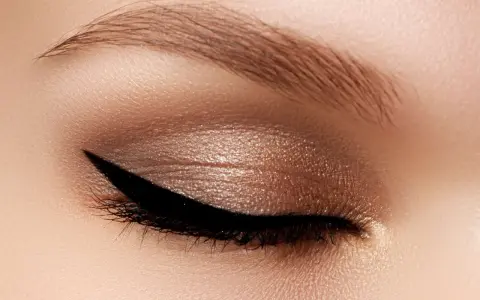 Occhio con trucco cat eyes, eyeliner nero definito e ombretto bronzo scintillante. Sopracciglio curato.