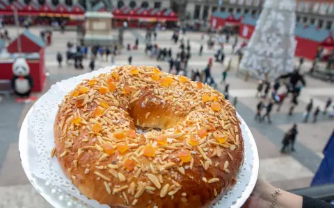 El mejor roscón de Madrid, adornado con almendras y fruta confitada, se presenta en la Plaza Mayor, un festín visual y delicioso.