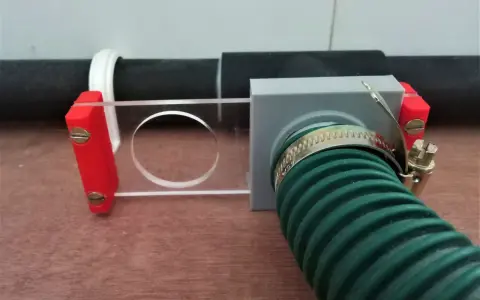 A 3d printed blast gate with a clear sliding mechanism and a green hose attached.