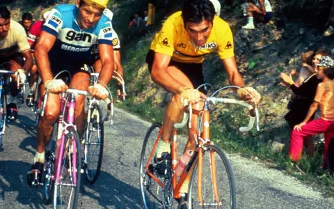 Eddy Merckx heute im Gelben Trikot, kämpft sich einen Berg hinauf. Fans jubeln am Straßenrand.
