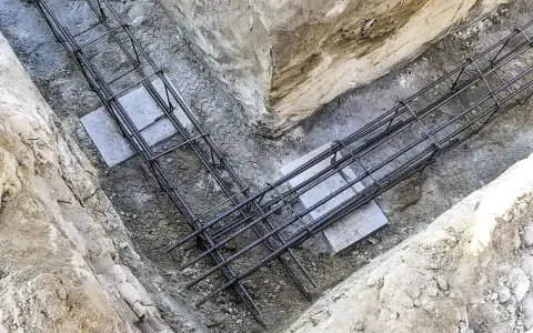 Gotowe zbrojenie ławy fundamentowej w wykopie. Stalowe pręty tworzą solidną konstrukcję, gotową na zalanie betonem.