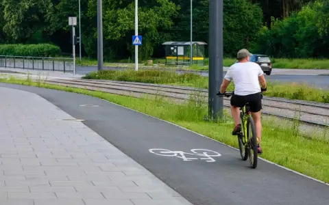 Mężczyzna na rowerze na ścieżce, obok torów tramwajowych. Uważaj, bo mandat za prowadzenie roweru pod wpływem alkoholu jest wysoki.