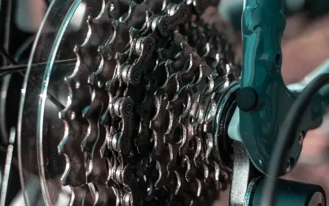 Zbliżenie na kasetę zębatek rowerowych i mocowanie przerzutki tylnej. Metalowe zębatki i łańcuch tworzą skomplikowany mechanizm.