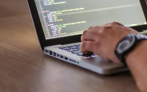 Ręce programisty piszącego kod na laptopie. Tester stron internetowych sprawdza poprawność wyświetlania elementów.