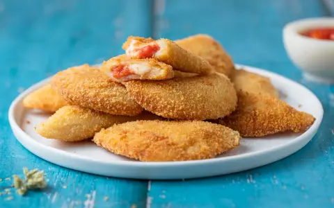 Sofficini fatti in casa dorati e croccanti, ripieni di pomodoro e formaggio filante, pronti per essere gustati.