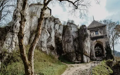 Ojcowski Park Narodowy atrakcje: ruiny zamku na skale, kamienna wieża bramna i ścieżka wśród zieleni.
