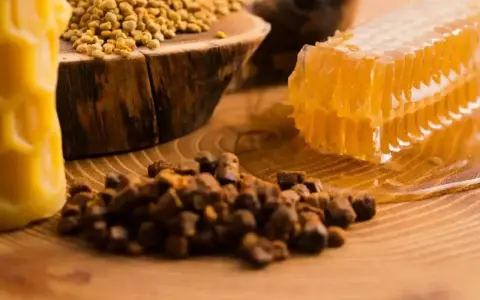 Propolis, pollen, et rayon de miel sur fond de bois. Découvrez les nombreux propolis bienfaits pour la santé.