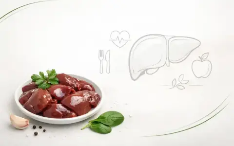 Surowa wątróbka na talerzu, obok czosnek i szpinak. Grafika wątroby i serca sugeruje, czy wątróbka jest zdrowa.