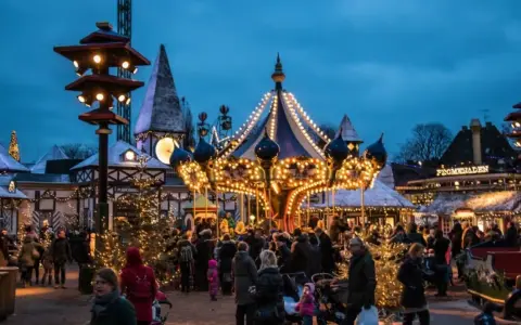 A lively Copenhagen Christmas market at dusk, with a brightly lit carousel and festive stalls. People stroll amongst decorated trees, enjoying the magical atmosphere.