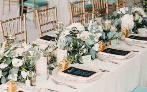 Elegancki obiad po ślubie cywilnym. Złote krzesła, zielone kieliszki i bukiety białych kwiatów tworzą romantyczną atmosferę.