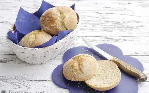 Frisch gebackenes, weiches Brot liegt in einem Korb und auf einem lila Brett. Ein Messer liegt daneben.