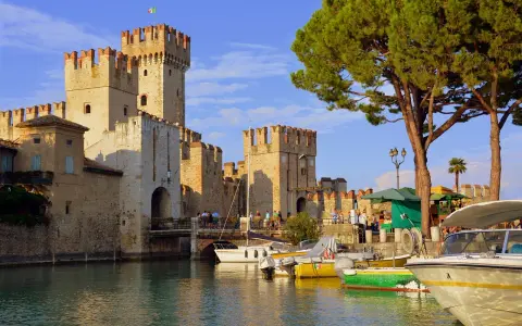 Castello Scaligero sul lago, ideale per vacanze in Lombardia. Barche ormeggiate in un porto pittoresco.