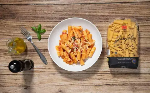 Macarrones a la napolitana servidos en un plato blanco, con un paquete de pasta Garofalo al lado.