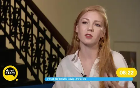 Marianna Kowalewska w białej koszuli, z rudymi włosami i złotymi kolczykami, opowiada o swoich pasjach na tle schodów.