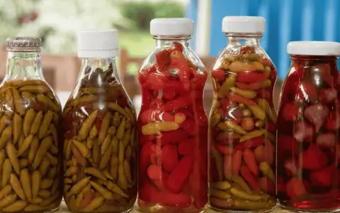 Bouteilles de piments verts et rouges marinés, prêts pour une recette de pickles maison.
