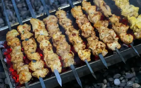 Aromatyczny kebab z kurczaka na rozżarzonych węglach. Soczyste kawałki mięsa pieką się na szpikulcach, tworząc apetyczny widok.